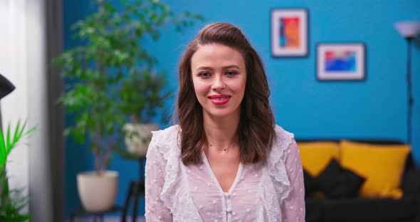 Portrait of a Pretty Young Woman Sitting at a Desk in a Living Room alt