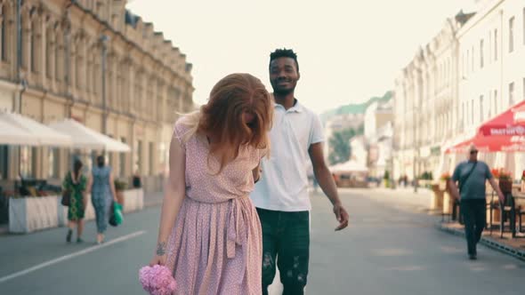 Young Happy Woman Leads Her Boyfriend's Hand Along City Street