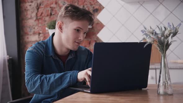 Disabled Man Sitting in Wheelchair in Apartment and Using Computer for Chatting Browsing Internet