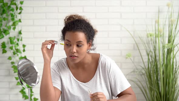 Portrait of young woman, applying beauty serum under her eyes