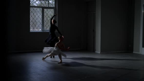 Two Flexible Ballerinas Rehearsing Performance in Darkness Indoors