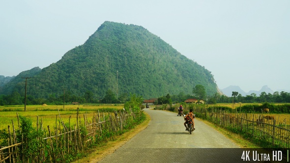 4K Remote Countryside Road in Southeast Asia with Motorcycle Traffic Rice Fields and Mountains