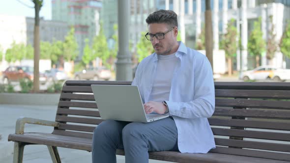 Busy Man Using Laptop Sitting Outdoor on Bench