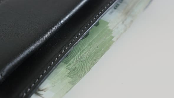 Wad of money in black leather wallet close-up 3840X2160 UltraHD tilting footage - Lot of euro bankno