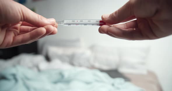 Male Hands Holding Analogue Thermometer with Very High Temperature