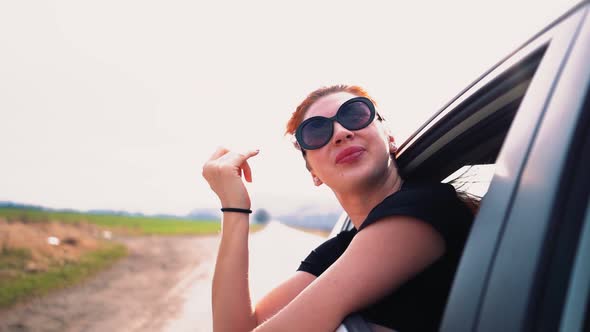 Happy Beautiful Girl Riding in the Back Seat of a Car Looks Out the Open Window