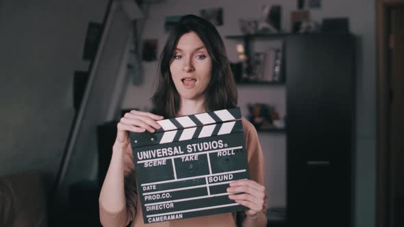 A beautiful girl holds a Clapperboard in her hands. Claps. Clicks. Winks at the camera. Flirting,