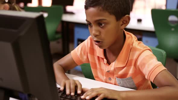 Schoolboy studying on personal computer in classroom