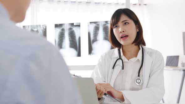 Young Asia female doctor using clipboard is discuss results or symptoms with male patient.