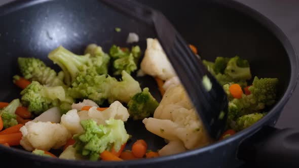 A woman cooking vegetables in a frying pan.