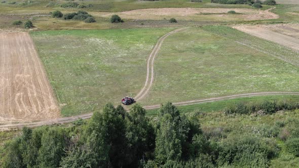 Aerial View of an Off-Road Vehicle Driving Down a Pathway in Rural Farmland