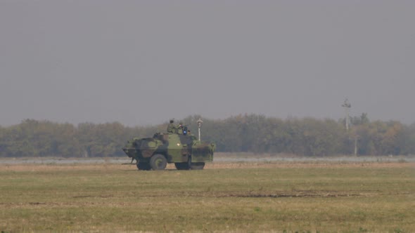 Green Mimecic Camouflage Military Vehicle Run at Fast Speed on the Battlefield.