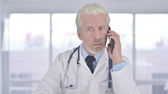 Portrait of Old Senior Doctor Talking on Smartphone in Clinic 
