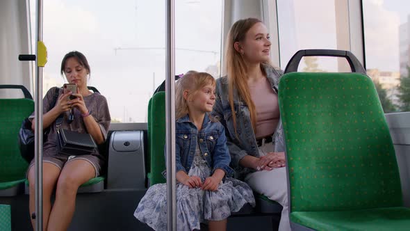 Family Rides in Public Transport Woman with Little Child Girl Sit Together and Look Out Window Tram