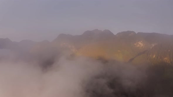 The Drone Flies Through the Clouds at the Mountain Peaks