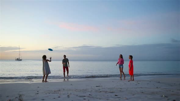 Happy Family Playing with Flying Disk at Beach at Sunset