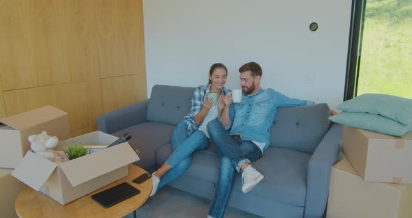 Panning Waist-up Shot of Pleased Smiling Caucasian Husband and Wife Relaxing and Drinking Tea