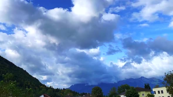 Footage of a twirling heavy clouds over the mountain and residential houses on the foreground.