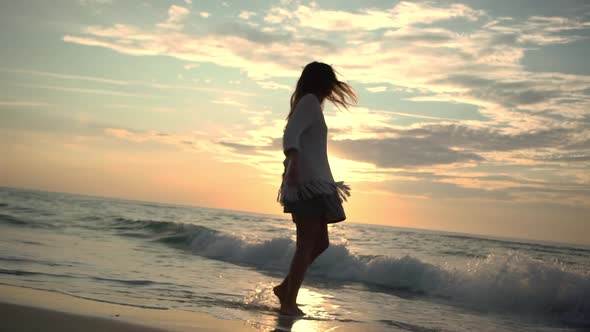 Happy Longhaired Girl Running on Water Along Empty Beach Feeling Free While Water Washing Over Her