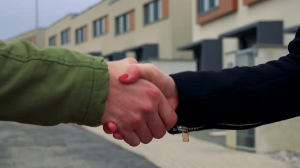 A Male and a Female Hands Shake, a Street in the Background - Closeup