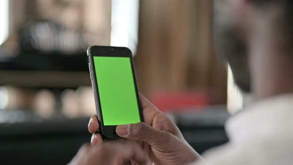 Rear View of African Man Using Smartphone with Chroma Key Screen 