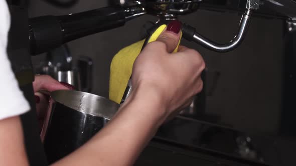 Female Barista Foams Milk for Cappuccino and Wipes the Steam Faucet with a Cloth