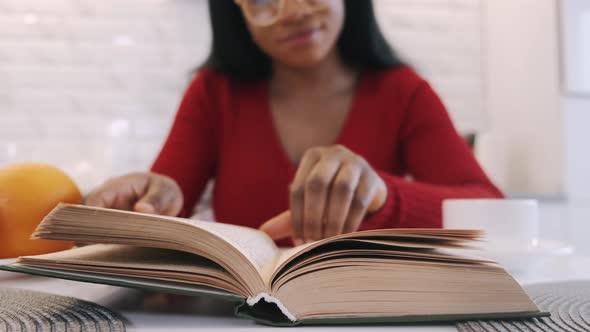 African American Girl Drinking Coffee and Studying at Home in the Kitchen