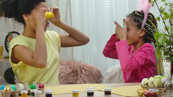 Mom and Daughter with Funny Bunny Ears Laugh and Have Fun with Colored Eggs