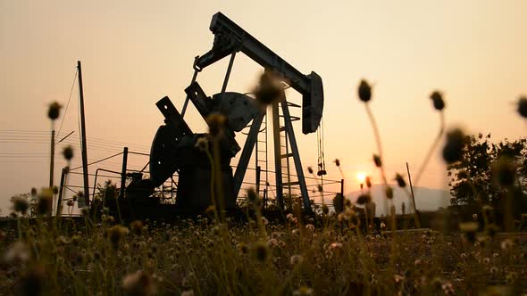 pumpjack at an oil drilling site and sunset