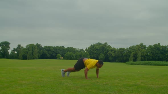 Active Sporty Fit African American Man Doing Burpees Workout on Green Field