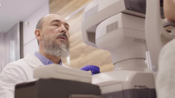 Senior Eye Care Specialist Using Autorefractor during Vision Test