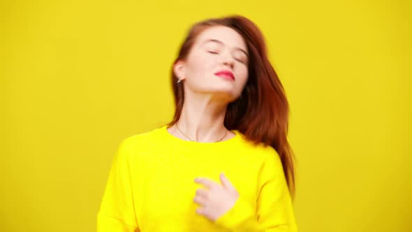 Carefree Beautiful Caucasian Woman Tossing Long Red Hair Posing at Yellow Background