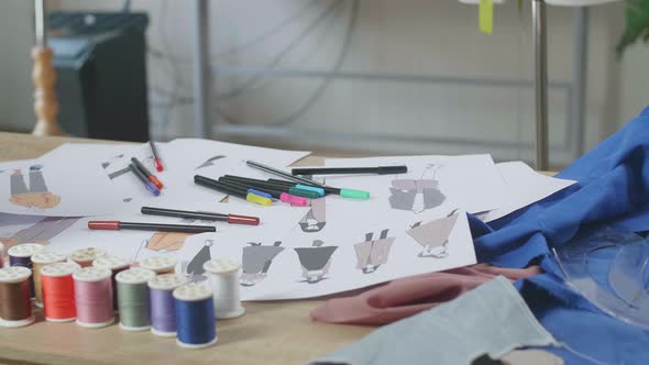 Clothes Drawing Pictures Are On The Table With A Sewing Machine In The Designer Studio