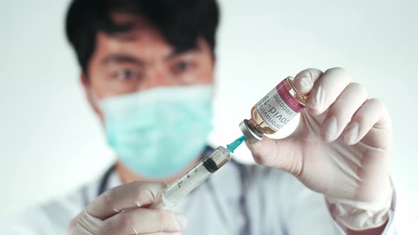 Asian Doctor Holding A Syringe With Liquid Vaccines