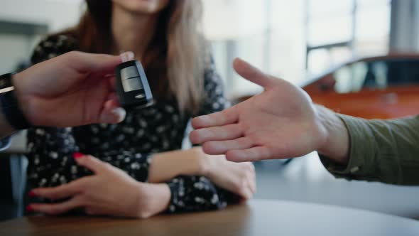 Closeup of the Hand of the Dealership Manager Who Gives the Customer the Keys to a New Car