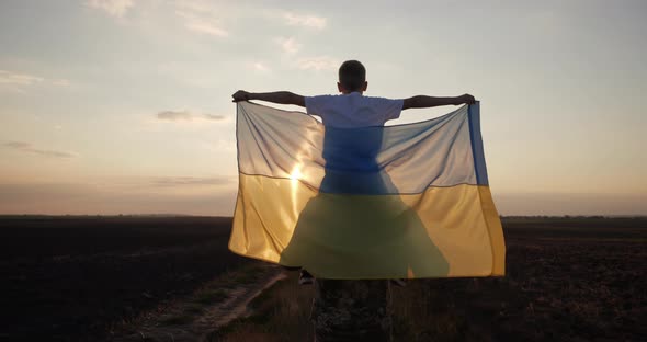 A Ukrainian Soldier Carries a Child in His Arms Holding the Flag of Ukraine