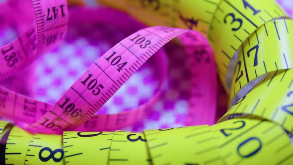 Close Up of a Pink and Yellow Measure Tape on Colored Rotating Background