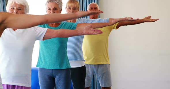 Trainer assisting senior citizens in practicing yoga