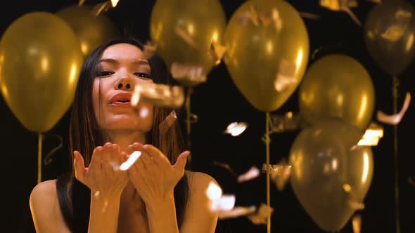 Attractive Asian Woman Sending Air Kiss to Camera Under Falling Confetti, Party