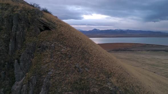 Flying towards and over mountainside viewing lake on cloudy day