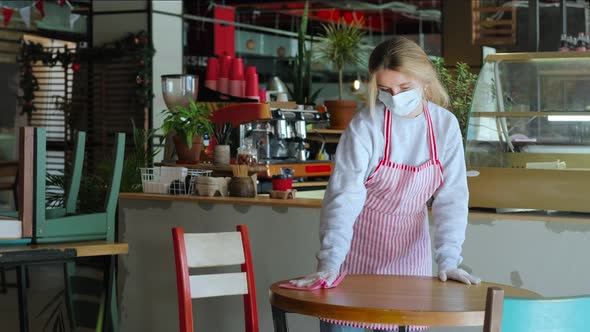 Waitress is Disinfecting Surface of Table in Cafe at Pandemic of Covid19 Wearing Mask and Gloves