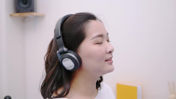 Asian teenage woman using the bluetooth headphone for listening to streaming music so lovely lie in