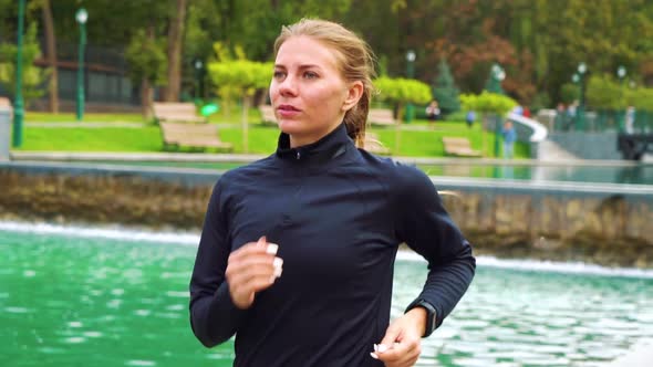 Young woman jogging near ponds in park