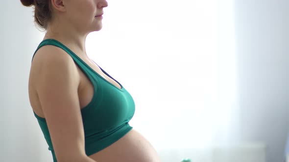 Pregnant Woman is Exercising with Dumbbells