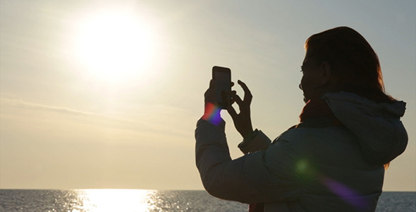 Woman shooting on Smartphone Sunset