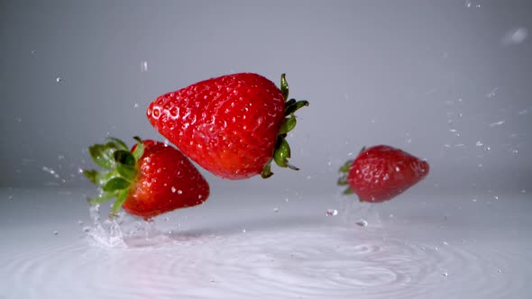 Strawberries falling on water surface. Slow Motion. alt