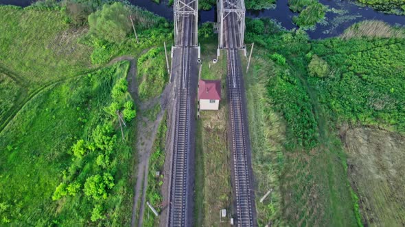 Small River Flows Smoothly Between Green Fields and a Railway Bridge