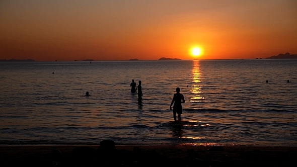 People in the Sea at Sunset