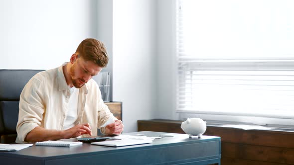 Professional accountant with beard counts paper checks summarizing sums on calculator