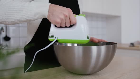 A Chef Beats Eggs with a Mixer in a Modern Kitchen